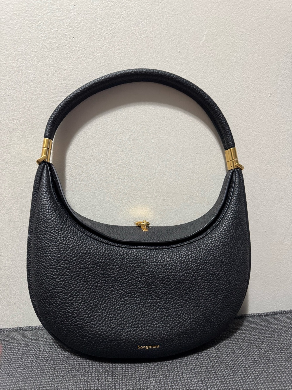 Songmont Black Pebbled Crescent Shoulder Bag with Gold Accents